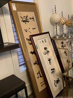 Two framed Asian calligraphy artworks leaning against a wall