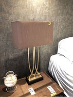 Front view of one lamp showing brown rectangular shade and gold-tone metal supports on a black base
