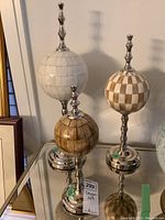 Three stone spheres of varying heights on silver metal stands.