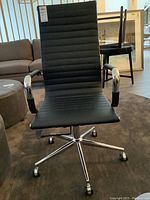 Front view of chair showing ribbed vinyl upholstery, chrome arms, adjustable lift mechanism, and caster base.
