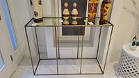 Wide front view of metal framed hall table with decorative items on top