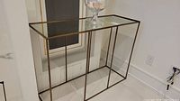 Front view of rectangular metal-framed table with brass-tone finish and mirrored top