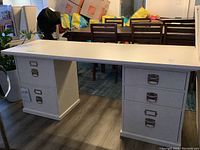 Frontal view of full desk showing rectangular white top with two pedestals