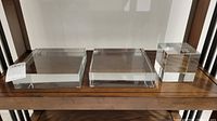 Three crystal display stands on wooden shelf: two large rectangular stands and one cube