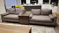 Two sofa pieces flanking a side table, showing overall configuration and upholstery color