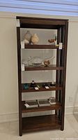 Front view of walnut bookshelf with five shelves, decorative items on shelves