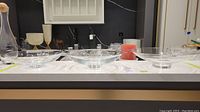 Three clear crystal fruit bowls displayed on a white surface. Two are similar size and slightly smaller, one is larger, all have a rounded shallow shape on a circular base.