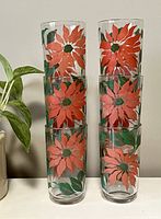 Front view of 6 stacked vintage glasses showing large red-orange floral print with green leaves on clear glass.