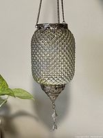 Front view of silver iridescent lantern showing textured glass body and metal decorations with hanging chain