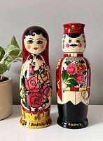 Pair of Russian Rodnik Matreshka dolls displayed side by side with a potted plant