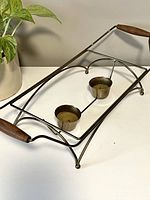 Front perspective view of brass food warmer showing rectangular frame, wooden handles, and candle holders.