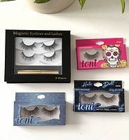 Top down view showing magnetic eyeliner with 2 pairs of magnetic lashes in black packaging alongside three sets of Ioni faux mink lashes in pink, blue and light blue packaging.