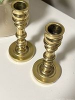 Pair of vintage brass candlesticks viewed from above showing tops and bases with patina.