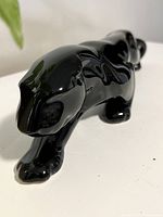 Front angled view of glossy black panther statue, showing its crouching posture and shiny smooth finish.