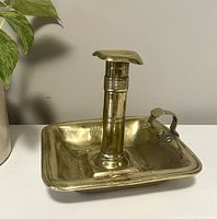Front and side view of the vintage brass chamber style candlestick holder showing the square tray base, handle, and central adjustable candle holder column.
