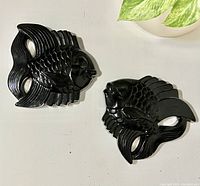 Pair of black chalkware fish wall hangings facing each other on a white surface, showing overall shape and finish.