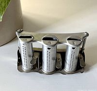 Front view of vintage metal coin change holder, showing three compartments marked 10, 5, and 1 with dispensers on a flat base