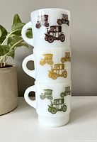Stacked view of three Fireking mugs showing brown, gold, and green antique car designs.