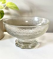 Side view of large clear crystal bowl with textured surface and thick solid foot