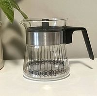 Front view of the Pyrex small tea pot showing the patterned glass body, metal band, and black handle.