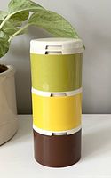 Stacked view of three vintage Tupperware spice containers in olive green, yellow, and brown with white lids.