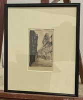 Framed vintage etching showing detailed cityscape with signature and date visible in lower margin.