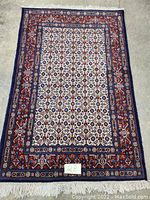 Full view of Persian hand-knotted wool rug laid flat showing overall pattern and condition