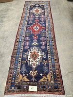 Full view of navy tribal runner laid flat on concrete floor