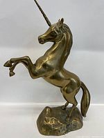 Side view of bronze unicorn figurine in rearing pose, showing profile details and base