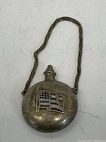 Top front view of the vintage metal compact showing the American flag decoration and attached chain.