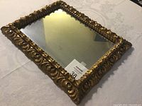 Image of the carved wooden mirror angled to show detailed gold carving and embedded mirrors on the frame edges.