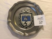 Image of a pewter plate with the crest from Bockenheim an der Weinestrasse, Germany. Shows detailed close-up of the coat of arms and scalloped rim.