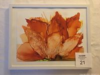 Framed alcohol ink painting showing abstract lilies in warm shades, signed by artist Gabriele Craig.