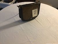 Angled side view of the beige and brown leather purse showing structure and clasp.