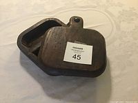 Closed wooden utensil showing dark wood with lid and knob, labeled with lot number sticker.