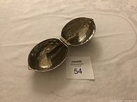 Silver metal nutcracker opened, showing the cracking mechanism inside and the hinge.