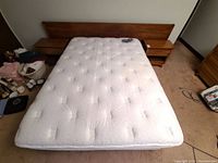 Wide shot showing headboard mounted on wall, queen mattress set on frame and both night tables flanking bed.