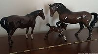 Photo showing three horse figurines lined up on a surface: the Beswick bay mare, the Royal Doulton bay gelding, and the foal.
