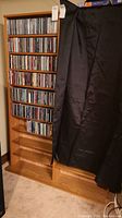 Full view of the wood veneer CD storage shelf partially covered with black cloth, adjustable shelving visible with several shelves empty at bottom.