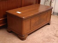 Front and right-side view of closed cedar chest showing carved trim and bracket feet