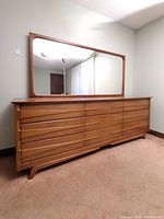 Three-quarter view of wood dresser with attached mirror in room