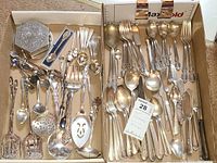 Overall box view showing assorted silverplate flatware, souvenir spoons, coaster set, napkin holders