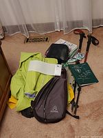 Overall view of lot showing yellow-green rain jacket, yellow rain jacket, hiking poles, Aegla daypack, binoculars, Tilley vest, guidebooks.
