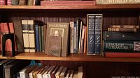 Books arranged on wooden shelves showing a variety of literature books including Shakespeare, Poe, Frost, and the Oxford Companion to English Literature with bookends
