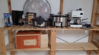 Shelf display of all items described including coffee grinder box, coffee maker, slow cookers, roaster, espresso machine