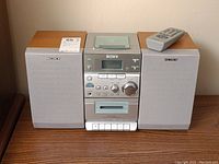Full view of Sony micro hi-fi system with 2 wooden speakers and remote control on top.