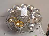 Overview of complete lot on glass platter: six stemmed cups, pedestal bowl, creamer, sugar bowl, hot water pot