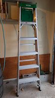 Full view of the 6-foot aluminum step ladder showing the steps, frame, and green tool tray on top.