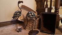 Two metal bird sculptures in front of stacked wicker and seagrass baskets and faux leather box