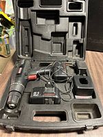 Open carrying case showing Craftsman cordless drill, two 12V batteries, and charger neatly placed inside molded plastic compartments.